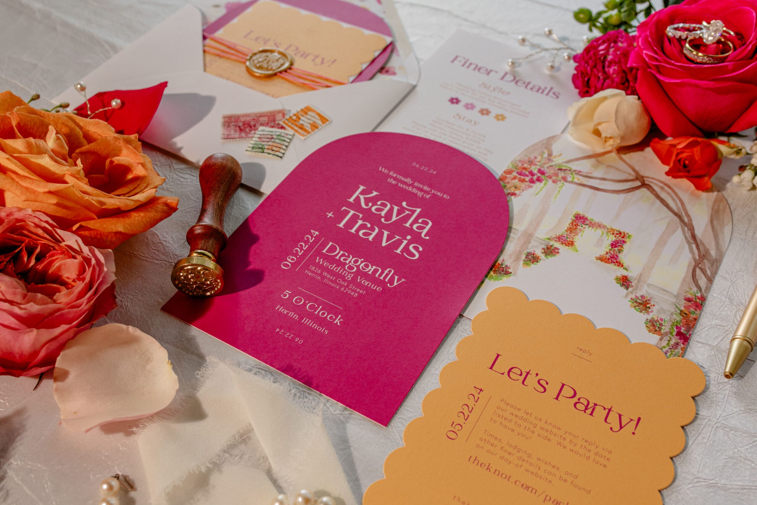 A romantic flat lay of a wedding invitation suite in soft pink and apricot hues, adorned with delicate flowers and scattered petals. The wedding rings rest elegantly among the floral accents, completing the timeless composition.