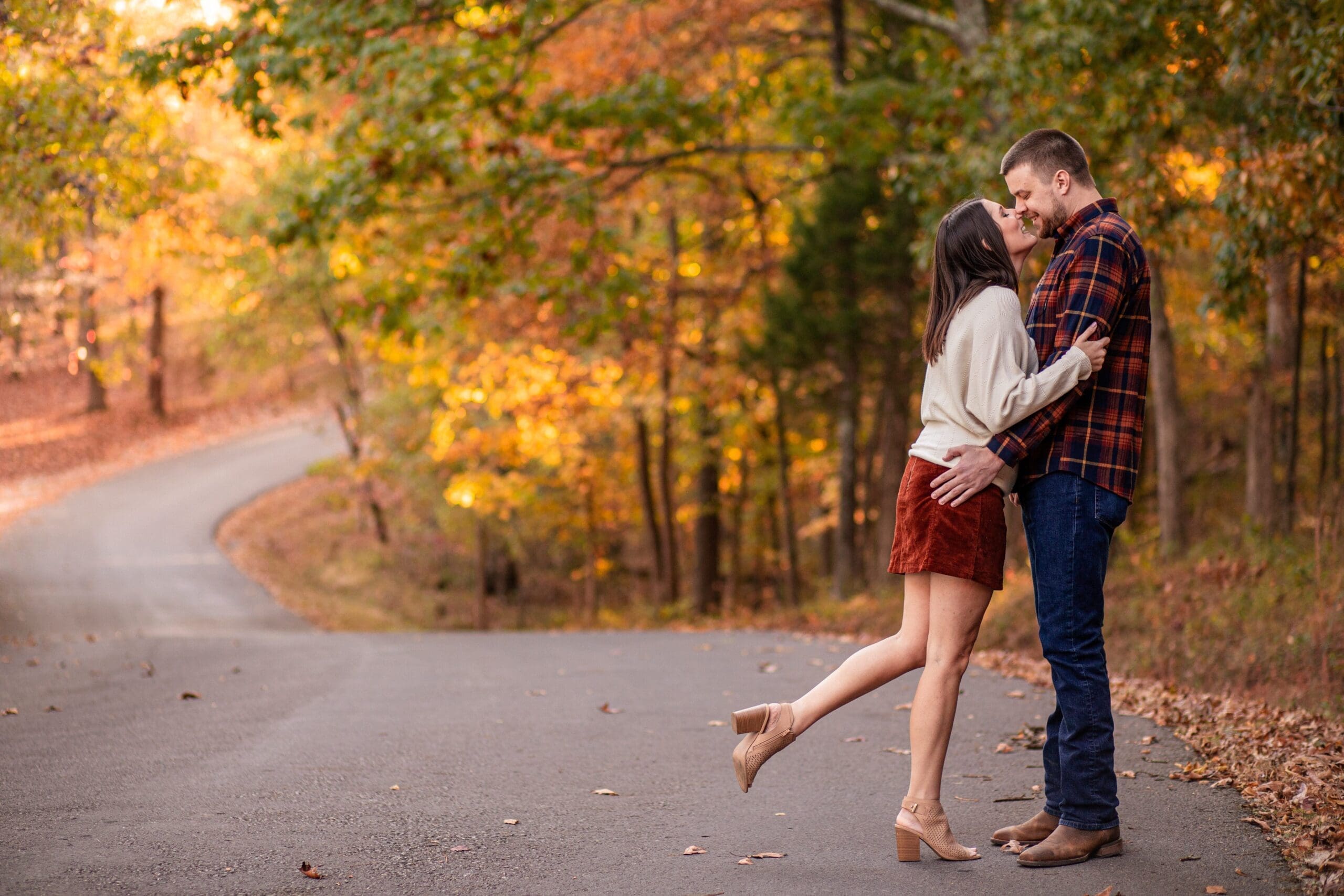 Couple standing in winding road kissing.